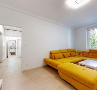 A living room with a striking yellow sofa and a wooden-patterned floor in a two-room apartment.