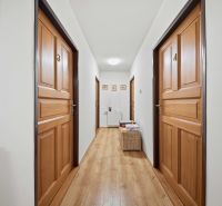 Hallway in a recreational apartment with doors and flooring featuring a wood design.