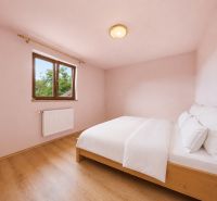 Bedroom in a holiday apartment with a window, bed, and wooden decor flooring.