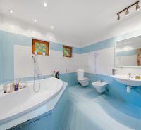 A bathroom with a corner bathtub, blue and white tiles in a Holiday Apartment.
