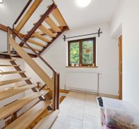 Wooden staircase in a holiday apartment with a window overlooking greenery.