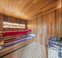 The interior of the sauna in the Recreational Apartment with wooden decor and lighting.