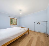 Recreational apartment with a simple bedroom, bed, wooden decor flooring, and a stand.