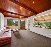 Living room with a wooden ceiling, brown sofa, and large windows in a Holiday Apartment.
