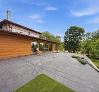 A recreational apartment in Trnava with a sunny terrace surrounded by greenery and wooden cladding.