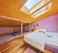 Attic bedroom with wood-patterned flooring and a skylight in a Holiday Apartment.