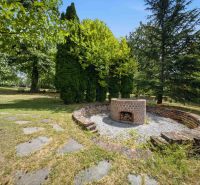 Garden fireplace with a stone path in a Recreational Apartment in Trnava, surrounded by trees.