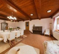 Interior of a holiday apartment with a dining table, piano, and wooden decor flooring.