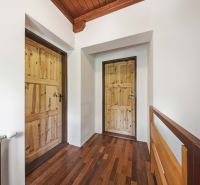 The interior of a holiday apartment with a wood-patterned floor and wooden doors.
