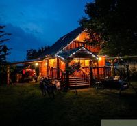 A family house in Lehota with wooden paneling illuminated by lights, garden swing.