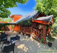 A log cabin in Lehoty with outdoor seating under trees in a pleasant natural environment.