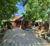 A family house in Lehota surrounded by greenery with a wooden terrace and outdoor seating.