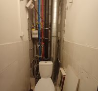 Bathroom in a 3-room apartment with a toilet and pipe installations on the wall.