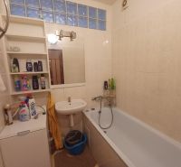 A bathroom in a 3-room apartment with built-in shelves, a sink, and a bathtub.
