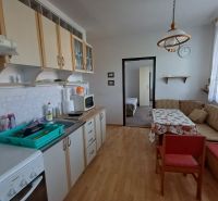 A kitchen in a 3-room apartment with a wooden decor floor and a corner sofa.