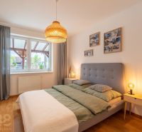A bedroom with a gray headboard and a wooden decor floor in a two-room apartment.