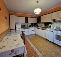 A kitchen in a family house with a wooden decor floor and a decorative tablecloth on the table.