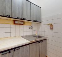 A kitchen unit with upper cabinets and a simple sink in a studio apartment.