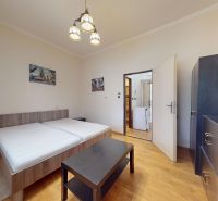 A bright bedroom with a bed, wardrobe, and wooden decor flooring in a studio apartment.