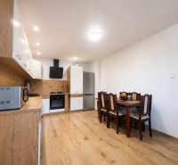 A kitchen with a dining table and a wood-patterned floor in a family house.