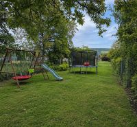 The garden of a family house on Gardom Street in the town of Veľký Šariš with a swing and a trampoline.