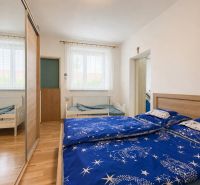 A bedroom in a family house with blue bed linen and a wooden decor floor.