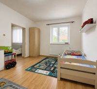 Children's room in a family house with a wooden decor floor, complemented by a carpet with a car track.