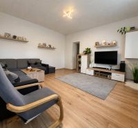 Living room in a family house with a comfortable sofa, TV, and wooden decor flooring.