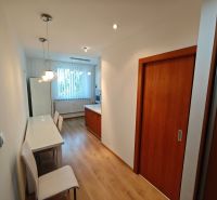 A kitchen in a one-room apartment with a wooden decor floor and a white table.