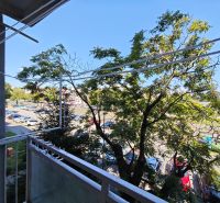 View from the balcony on Hollého Street in Michalovce with a parking lot and trees near a 1-room apartment.