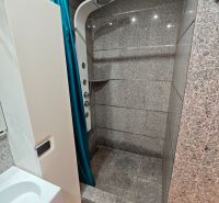 A shower corner with a blue curtain in the bathroom of a studio apartment.