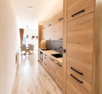 A kitchen in a 3-room apartment with a wooden decor floor and wooden kitchen cabinets.
