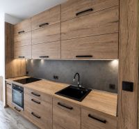 A kitchen in a 3-room apartment with a wooden decor kitchen unit and a cooktop.