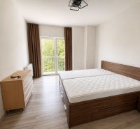 Bedroom with light walls, wood-patterned flooring, a large bed, and a dresser.