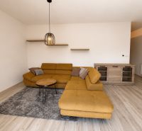 Living room with a sofa and wood-patterned flooring in a three-room apartment.