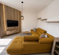 Living room with a mustard sofa, television, and wooden decor flooring.