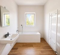 A bathroom with light walls, a bathtub, a sink, and a wooden decor floor, suitable for a 3-room apartment.