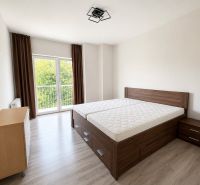 Bedroom with wood-patterned flooring in a 3-room apartment, light and view of greenery.