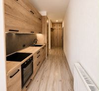 A narrow kitchen in a 3-room apartment with wooden decor and a radiator.