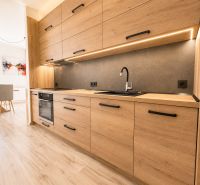A kitchen in a 3-room apartment with a wood-patterned floor and a dining area.
