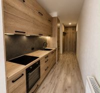 A kitchen with a wooden decor floor and furniture in a 3-room apartment.