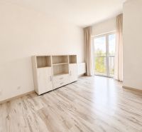 A room with a wooden decor floor and light furniture in a 3-room apartment.