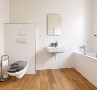 A bathroom in a 3-room apartment with a bathtub, toilet, and a floor with a wooden decor.