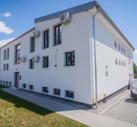 White modern building with a parking lot and air conditioning units in Zemplínska Šírava.