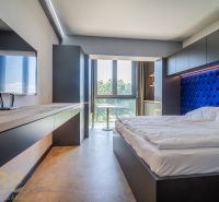 Bedroom in a holiday apartment with a bed and TV, large window provides a view.
