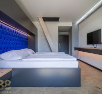 Bedroom in a holiday apartment with a blue headboard and a TV on the wall.