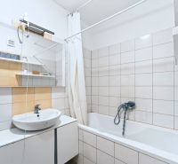 Bathroom with a bathtub and a sink in a 3-room apartment with tiles and tiling.