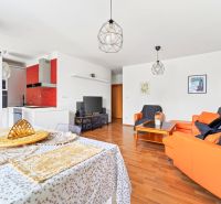 Living room with a sofa and a kitchenette in a 3-room apartment with a wooden decor floor.