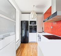 A kitchen in a 3-room apartment with orange mosaic and a wooden decor floor.