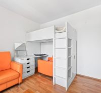 Children's room in a three-room apartment with a wooden decor floor and an orange armchair.